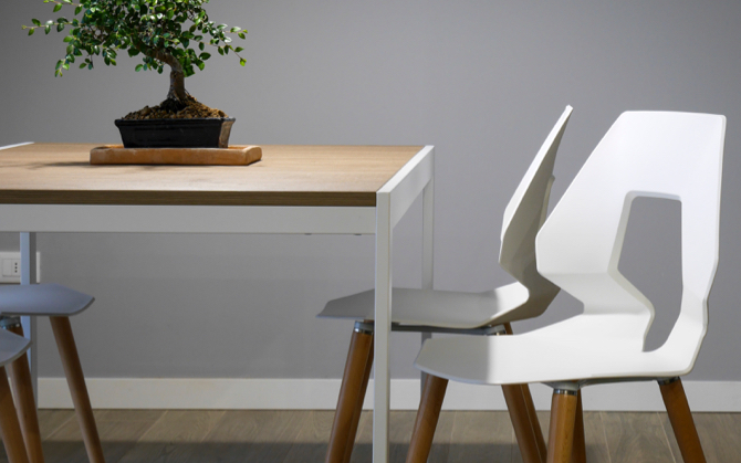 Three modern and white chairs surronding a table with a plant resting on it