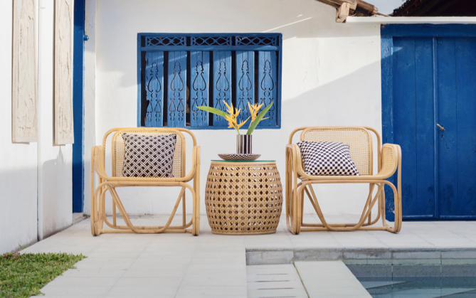 Two modern straw patio chairs outside infront of a white and blue styled home